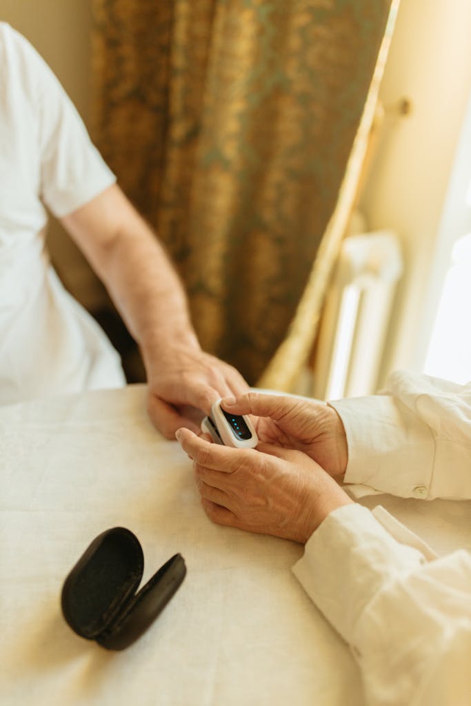 Care Services A senior adult using a pulse oximeter indoors to monitor health in a warmly lit room.