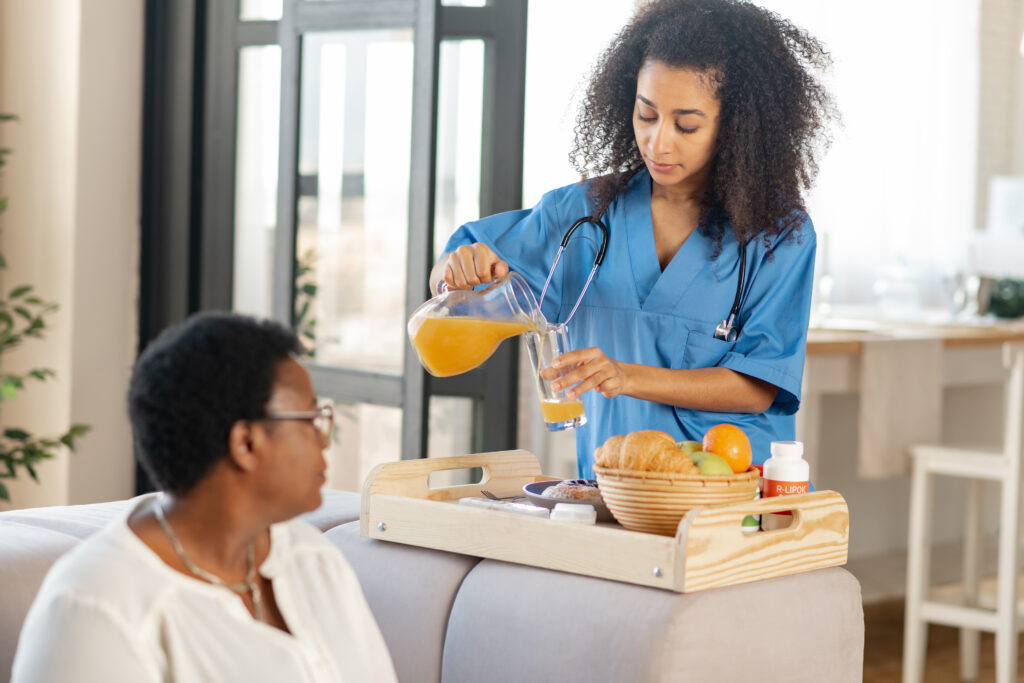 Holistic Care nurse pouring some orange juice for lady living in nursing house