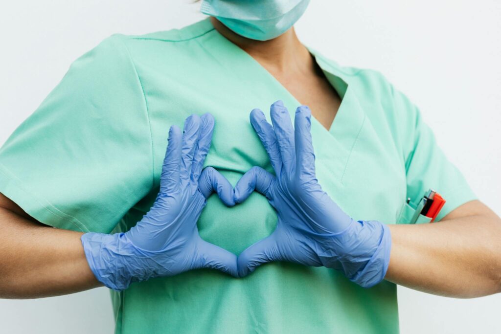 About Us Medical professional forming a heart shape with blue gloves. Symbol of care and compassion.